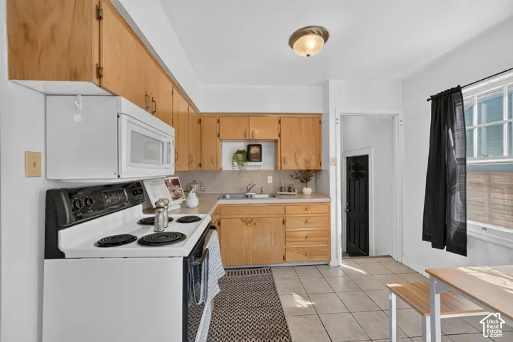 U-shaped kitchen layout with wood-finish cabinetry, tile flooring, and a window with natural light