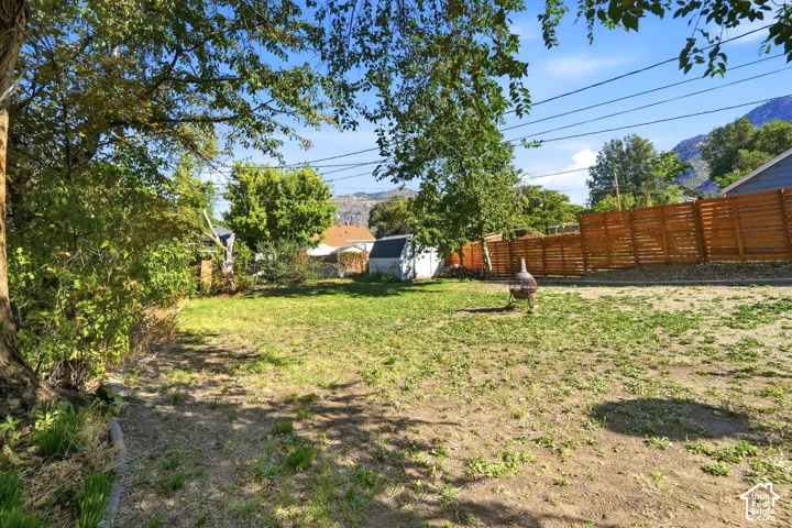 Expansive backyard featuring mature trees, wood fence, and a storage shed