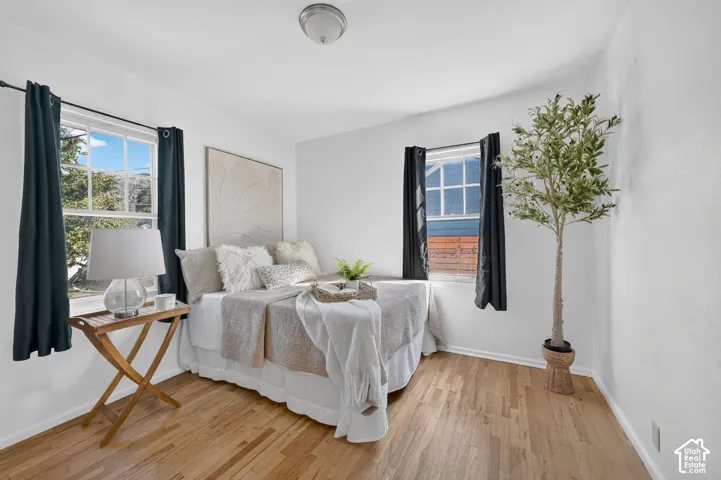 Hardwood flooring, painted white walls, two windows, and a flush mount ceiling light fixture