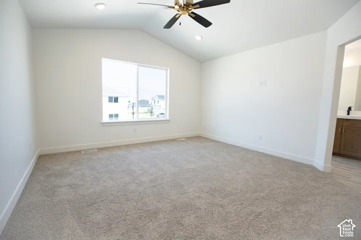 Primary bedroom with vaulted ceiling and ceiling fan.  Adjacent to a large walk-in closet as part of primary suite.