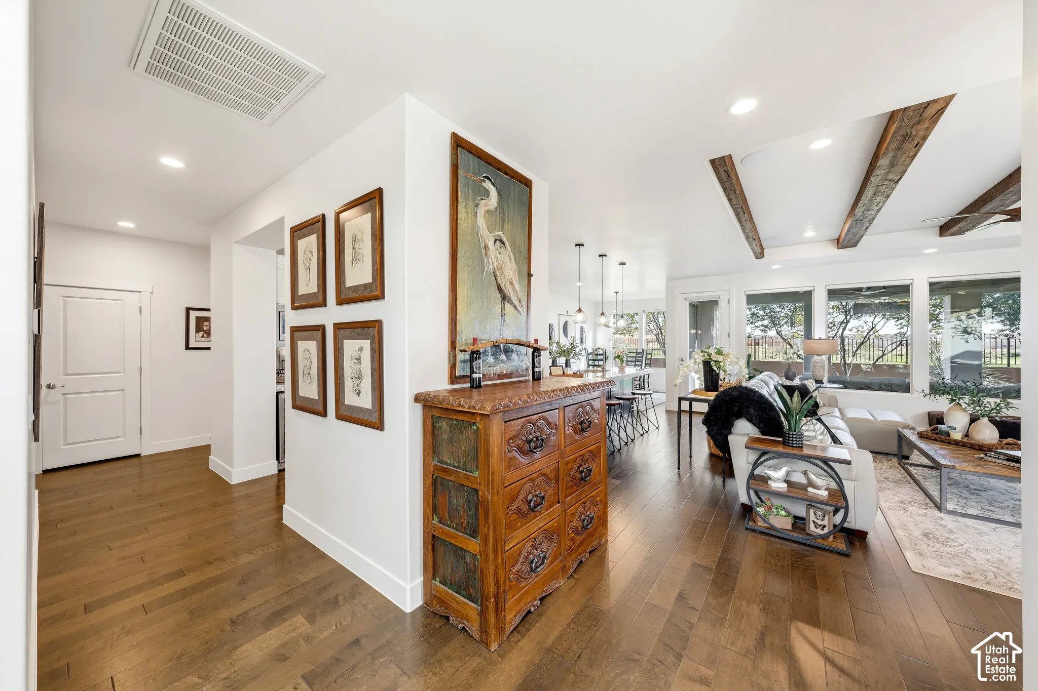 Hardwood flooring, white interior walls, recessed lighting, exposed ceiling beams, and large picture windows