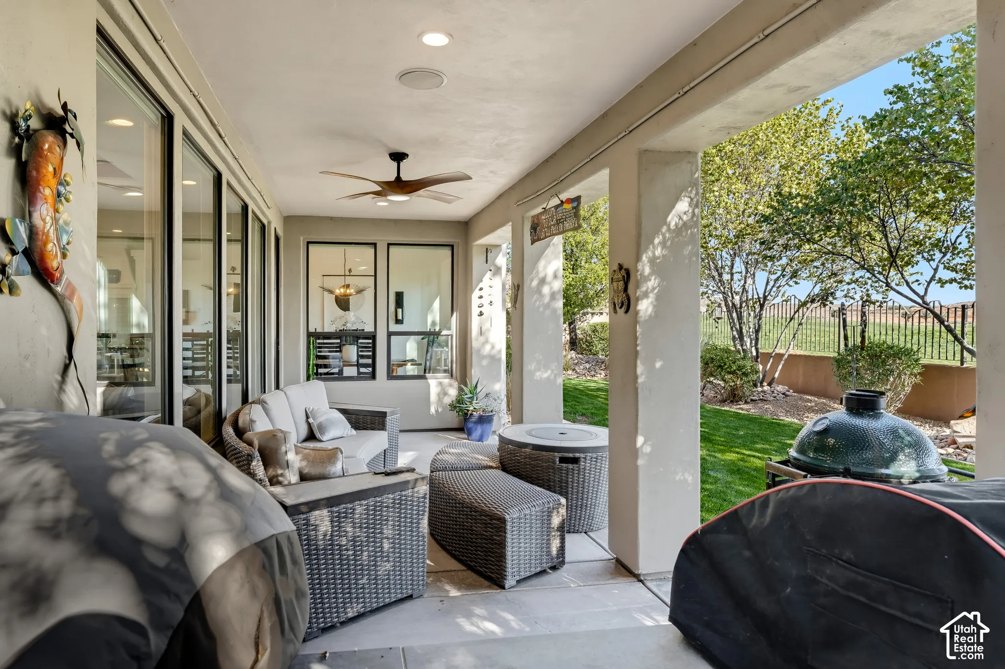 Covered patio with recessed lighting, ceiling fan, expansive glass sliding doors, and a manicured lawn