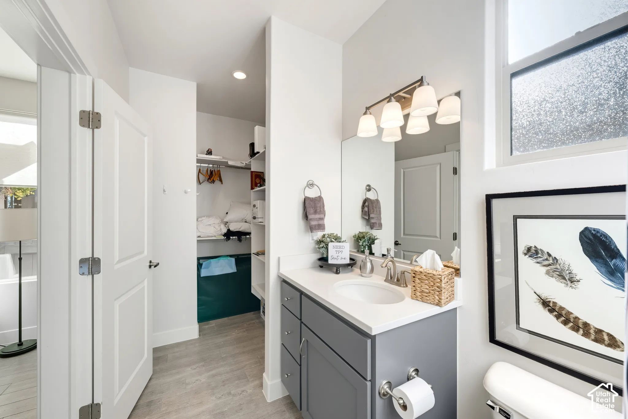 Spa-inspired primary bathroom featuring a gray vanity with white quartz countertop, chrome fixtures, and integrated storage