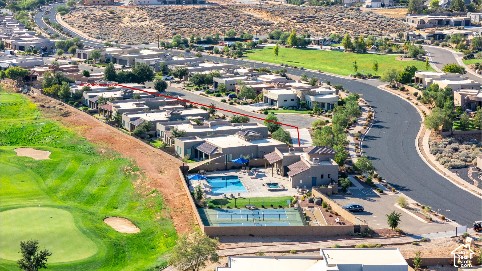 Aerial perspective showcasing a residential community with a large outdoor pool, tennis court, and manicured golf course