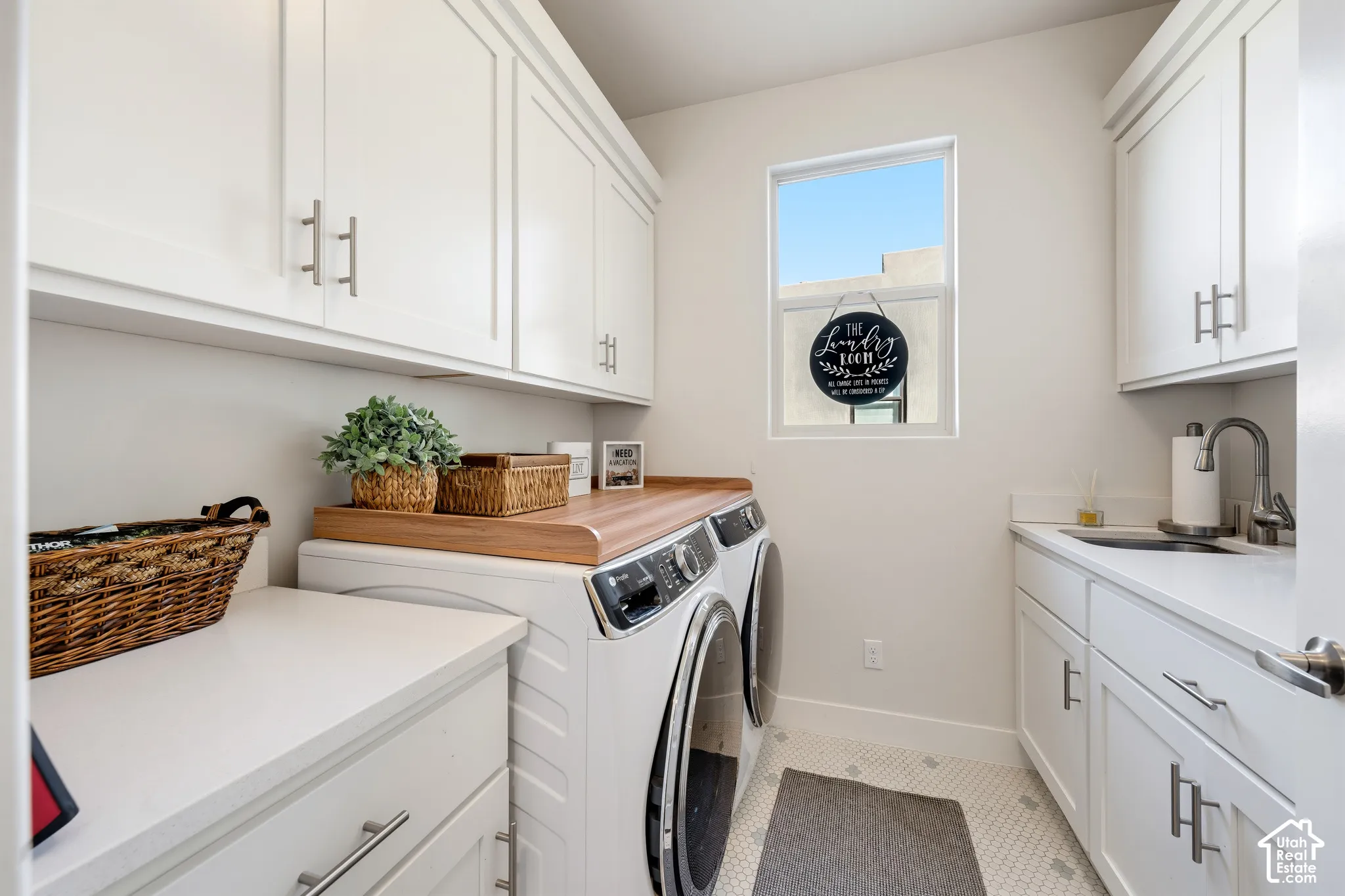 White shaker cabinetry, wood-finish countertop, undermount sink with a gooseneck faucet, hexagon tile flooring, and a single pane window