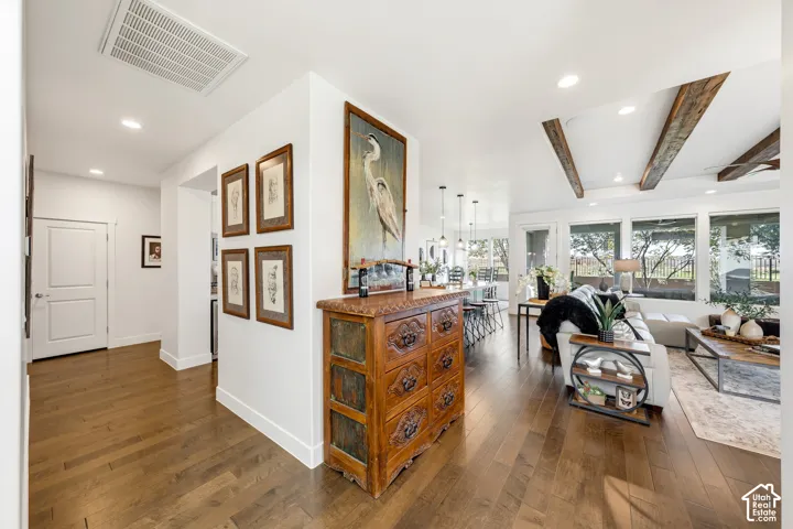 Hardwood flooring, white interior walls, recessed lighting, exposed ceiling beams, and large picture windows