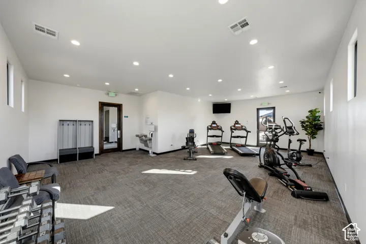Fitness center with recessed lighting, carpet flooring, multiple windows, and a wall-mounted television