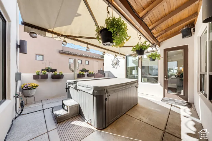Patio featuring a built-in spa, concrete flooring, and a wood-slat ceiling with a retractable awning