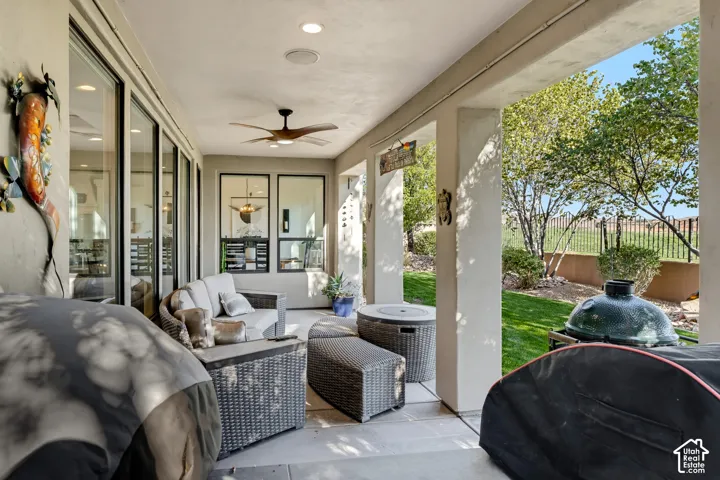 Covered patio with recessed lighting, ceiling fan, expansive glass sliding doors, and a manicured lawn