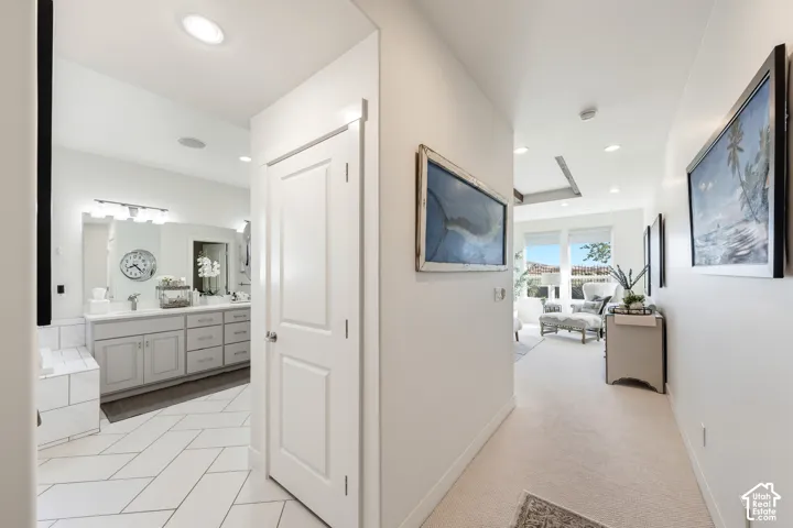 White shaker-style vanity with dual sinks, wall-mounted lighting, and a framed mirror