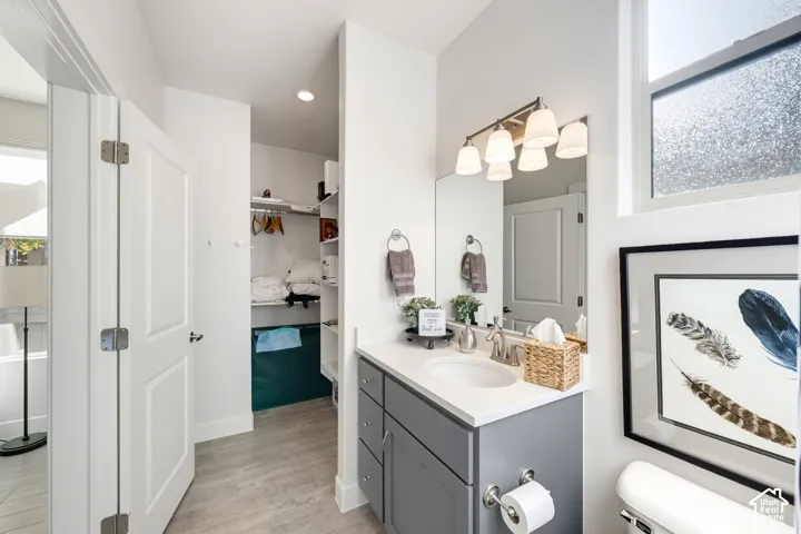 Spa-inspired primary bathroom featuring a gray vanity with white quartz countertop, chrome fixtures, and integrated storage