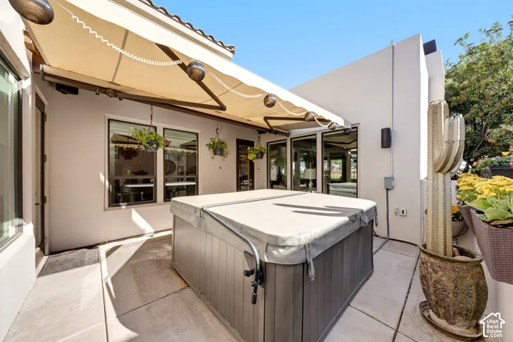 Patio with a retractable awning, integrated hot tub, and a decorative cactus sculpture