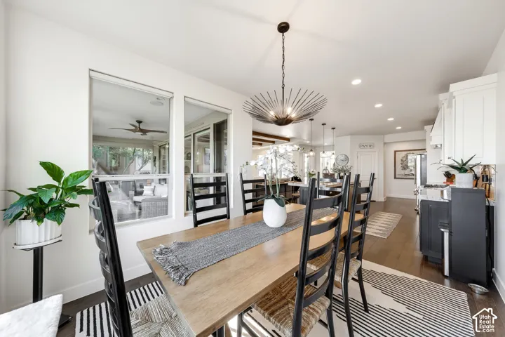 Dining area featuring a wood-finish table, black ladder-back chairs, and a sculptural pendant light fixture