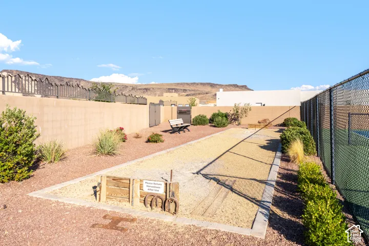 Expansive outdoor living space featuring a generous hardscaped patio with warm-toned pavers, mature landscaping with native vegetation, and metal fencing