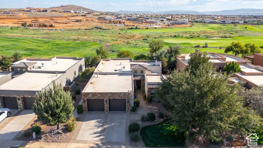 Stone facade residence with a two-car garage, manicured landscaping, and mature trees, set against a golf course backdrop