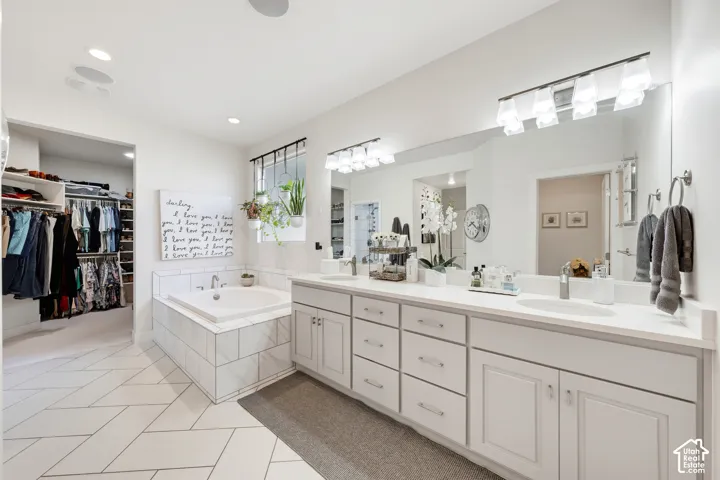 Dual vanity with integrated sinks, extensive cabinetry, and a large mirror