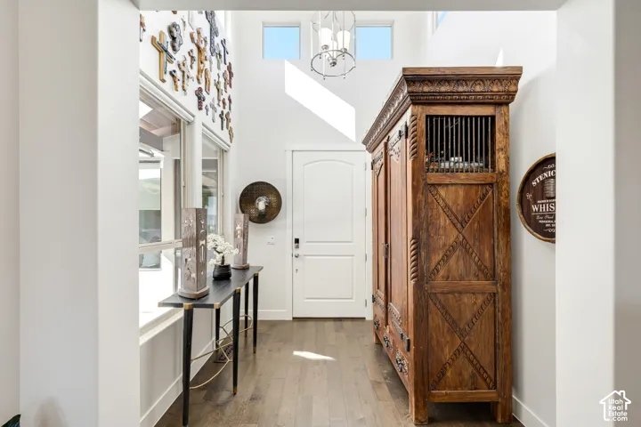 White interior walls with high ceilings, wood-finish flooring, transom windows, and a built-in chandelier