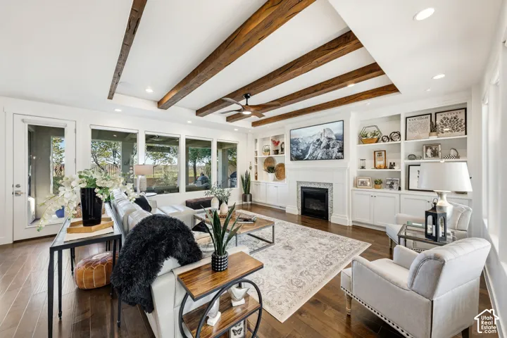 Bright, open-concept living space featuring exposed wood-beam ceiling details, wood-finish flooring throughout, and abundant natural light from multiple French doors and windows
