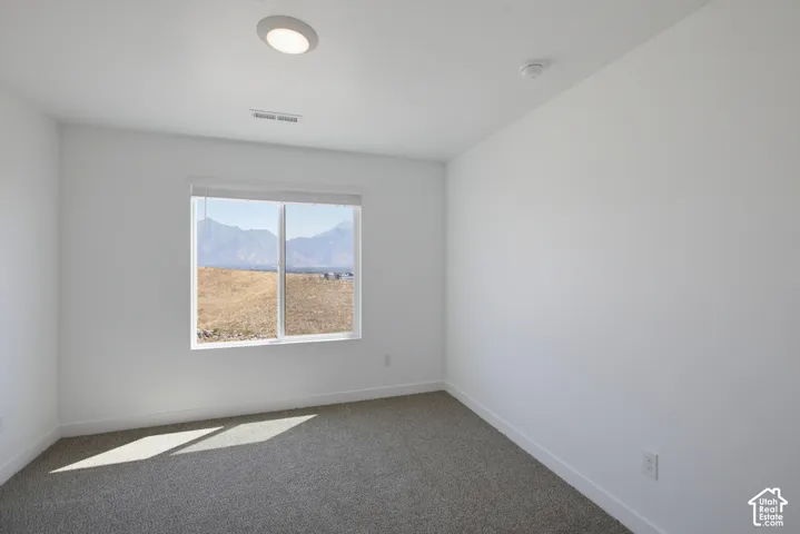 Light-filled room featuring a large window, neutral carpeting, recessed ceiling lighting, and a mountain backdrop