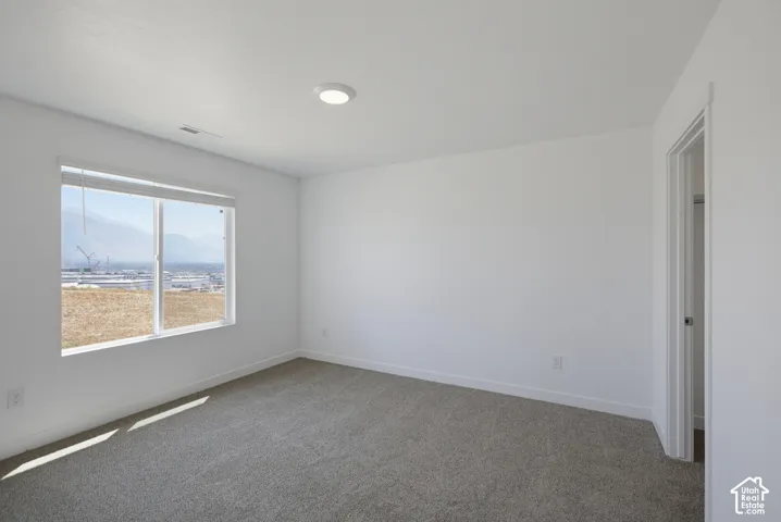Recessed ceiling lighting, white walls, gray carpet flooring, window with blinds, white trim