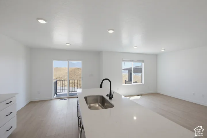 Open concept living area with recessed lighting, light wood-finish flooring, and a sliding glass door leading to a balcony