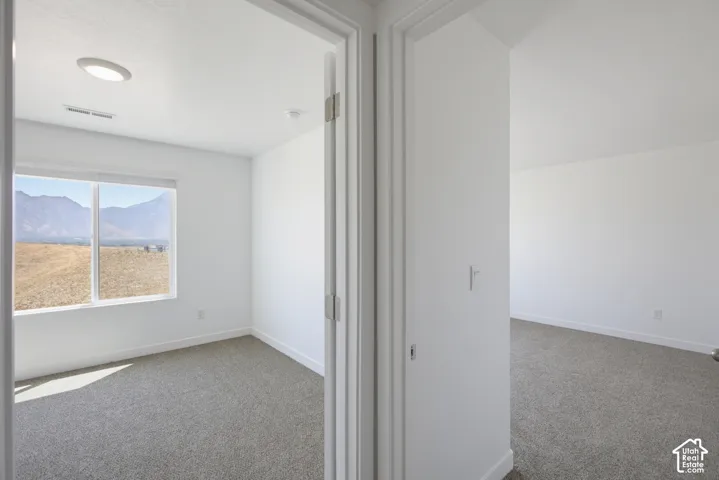 Room with mountain scenery through a window, recessed ceiling lighting, and grey carpeting