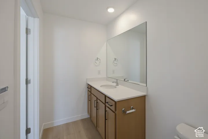 Single vanity with light-tone cabinetry, integrated sink, and wide mirror