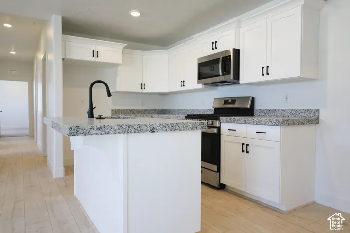 Terrific kitchen with painted white wood cabinets, granite slab countertops, gas range, microwave, dishwasher and disposal.