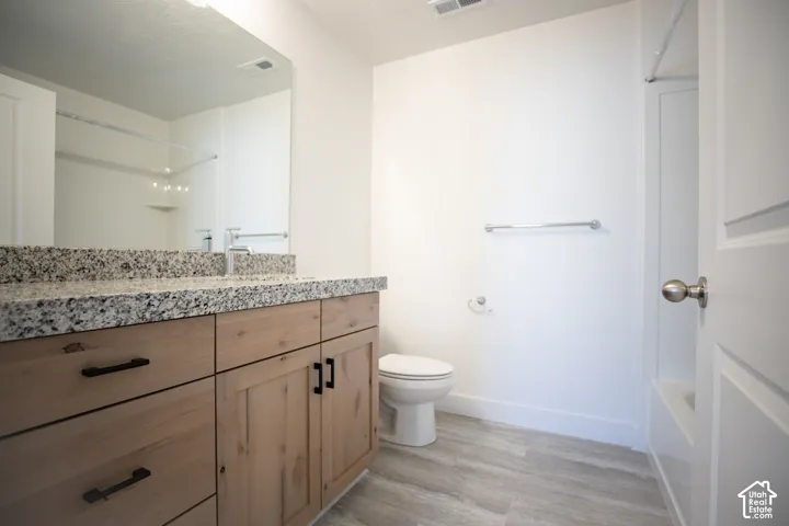Full secondary bath with stained wood cabinets and granite slab countertops.