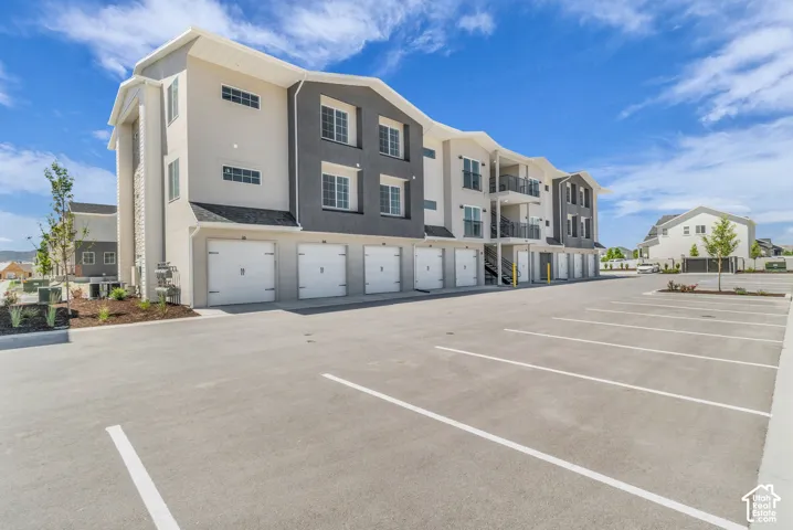 Rear view of building with garage for each unit and additional parking.