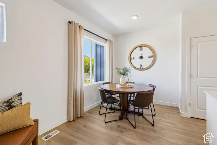 Bright dining area featuring wood-finish flooring, recessed lighting, and a window with natural light