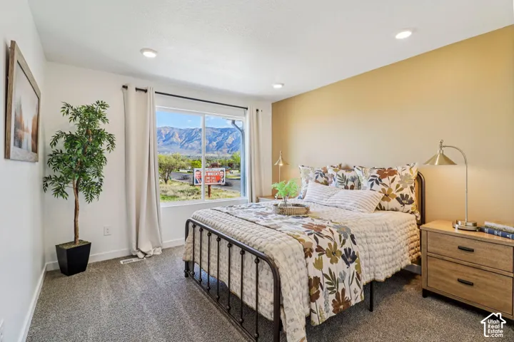 Recessed lighting, large window with mountain scenery, neutral wall tones, and textured carpeting