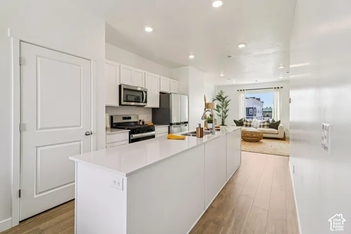 Kitchen featuring white cabinetry, stainless steel appliances, a large island with a sink, and recessed lighting