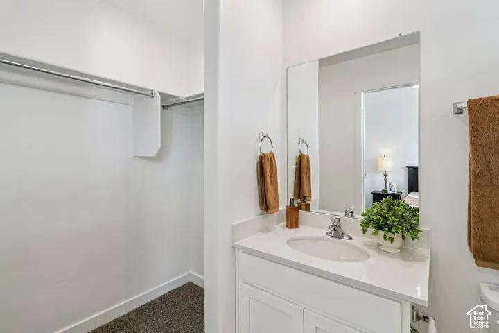 Built-in closet with hanging rod, vanity with single basin sink, and a framed mirror
