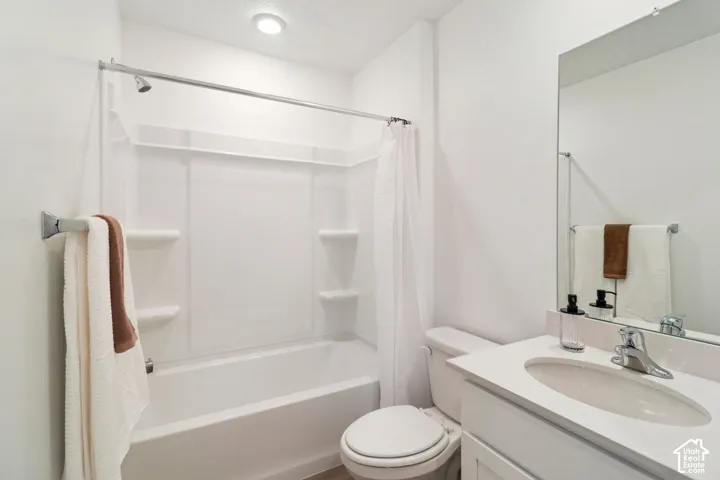 White bath and shower combination with integrated shelving, chrome showerhead, and recessed ceiling lighting