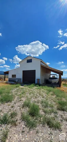 Barn-style structure with a large overhead door, attached carport, and upper-level window