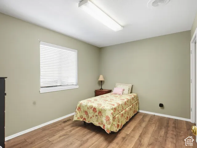Wood-finish flooring, neutral wall tones, white trim, and a window with blinds