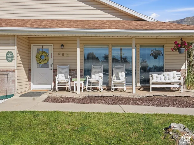 Covered front porch with siding and brick veneer, asphalt shingle roof, and multiple large windows