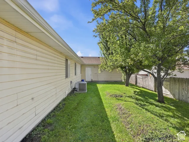 Expansive green space featuring mature trees, a wooden privacy fence, and vinyl siding