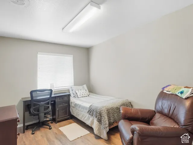 Wood-finish flooring, neutral wall paint, and a rectangular window with blinds