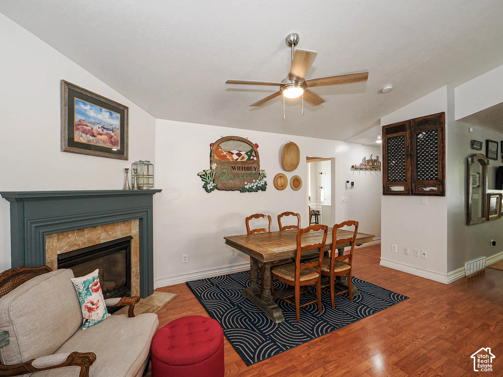 Interior space with wood-finish flooring, a fireplace featuring a stone surround and painted mantel, and a ceiling fan with integrated lighting