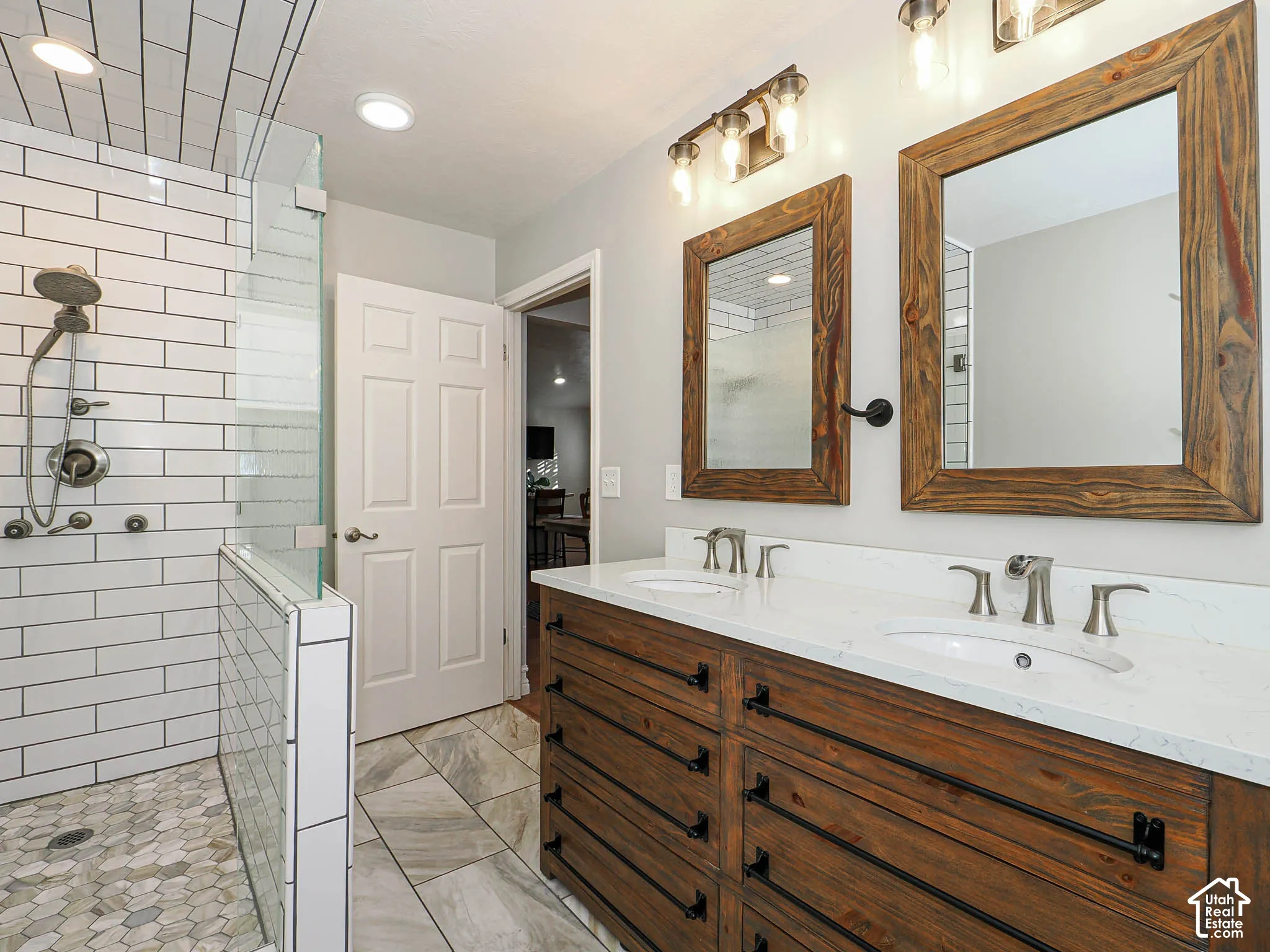 Glass-enclosed shower with subway tile surround and pebble-tile flooring