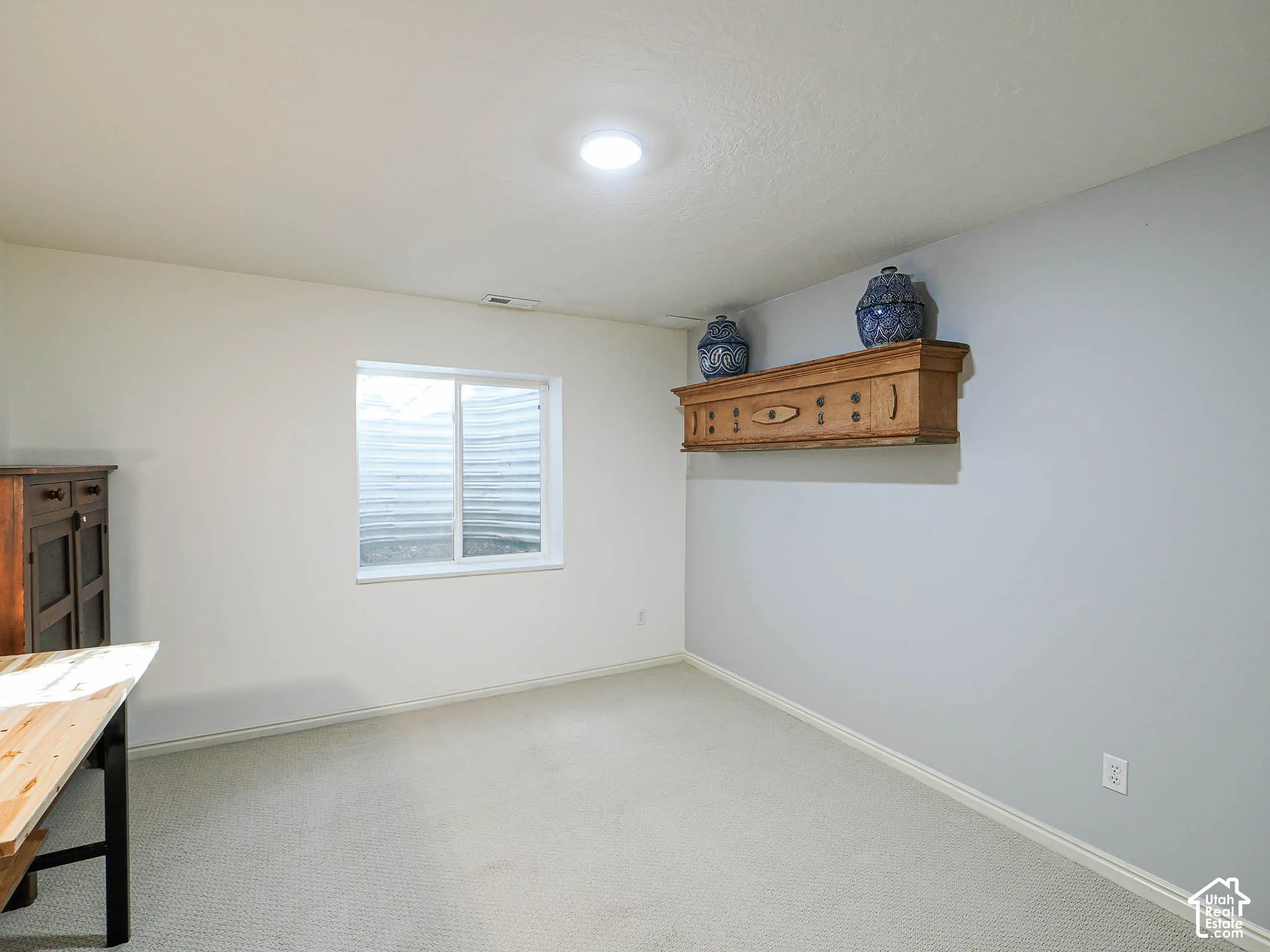 Recessed lighting, wall-to-wall carpeting, and a window with a well-cover