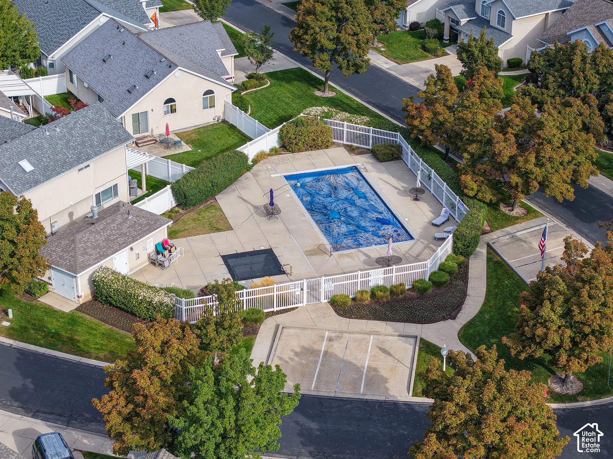 Community pool with surrounding concrete patio, white fencing, and integrated landscaping