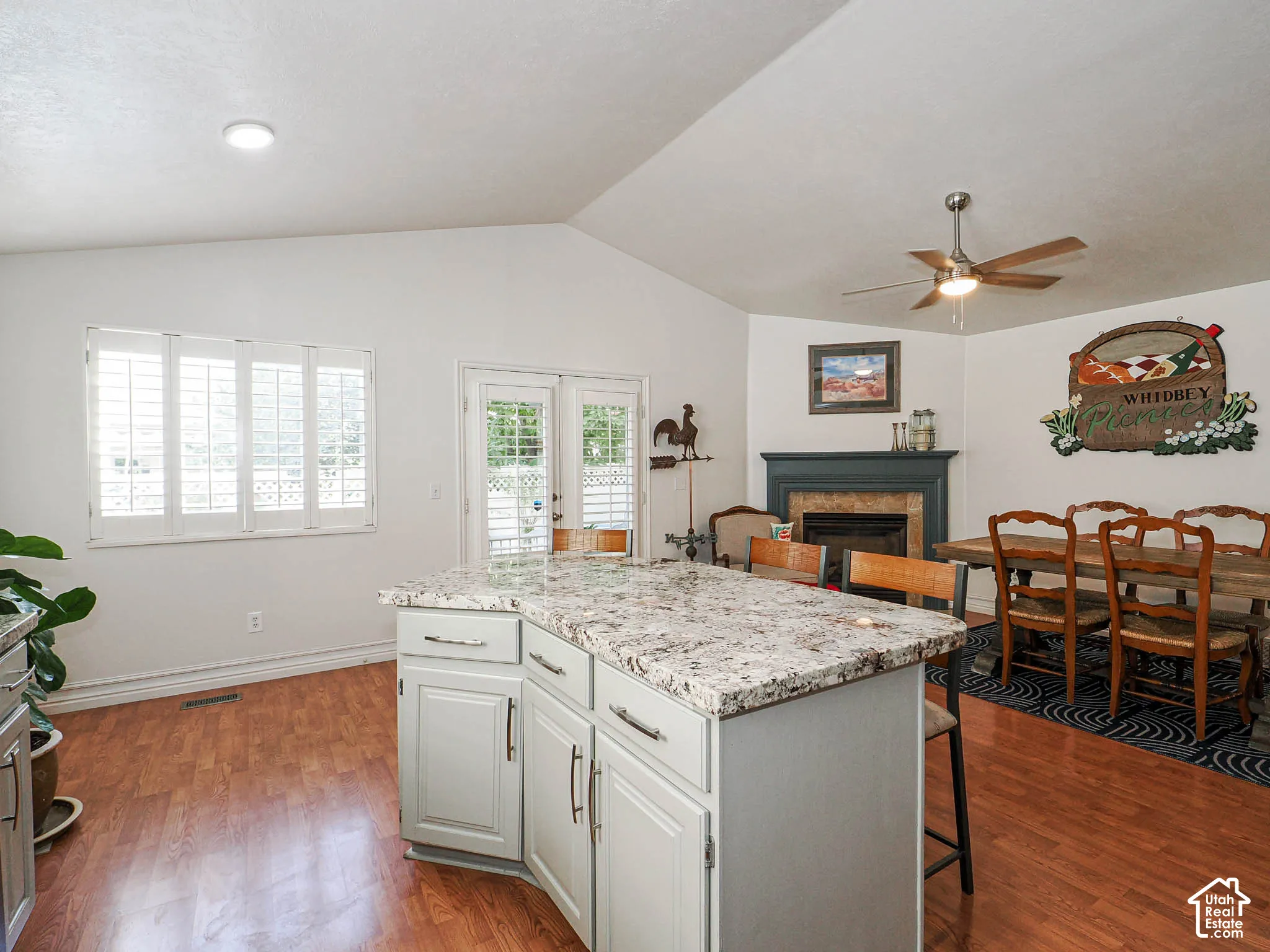 Kitchen island with a light-colored countertop, wood-finish flooring, and white cabinetry