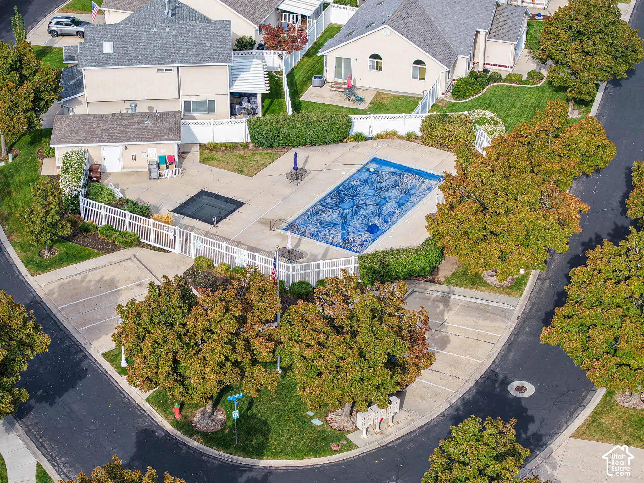 Community pool with a surrounding paved deck, fenced perimeter, and adjacent building