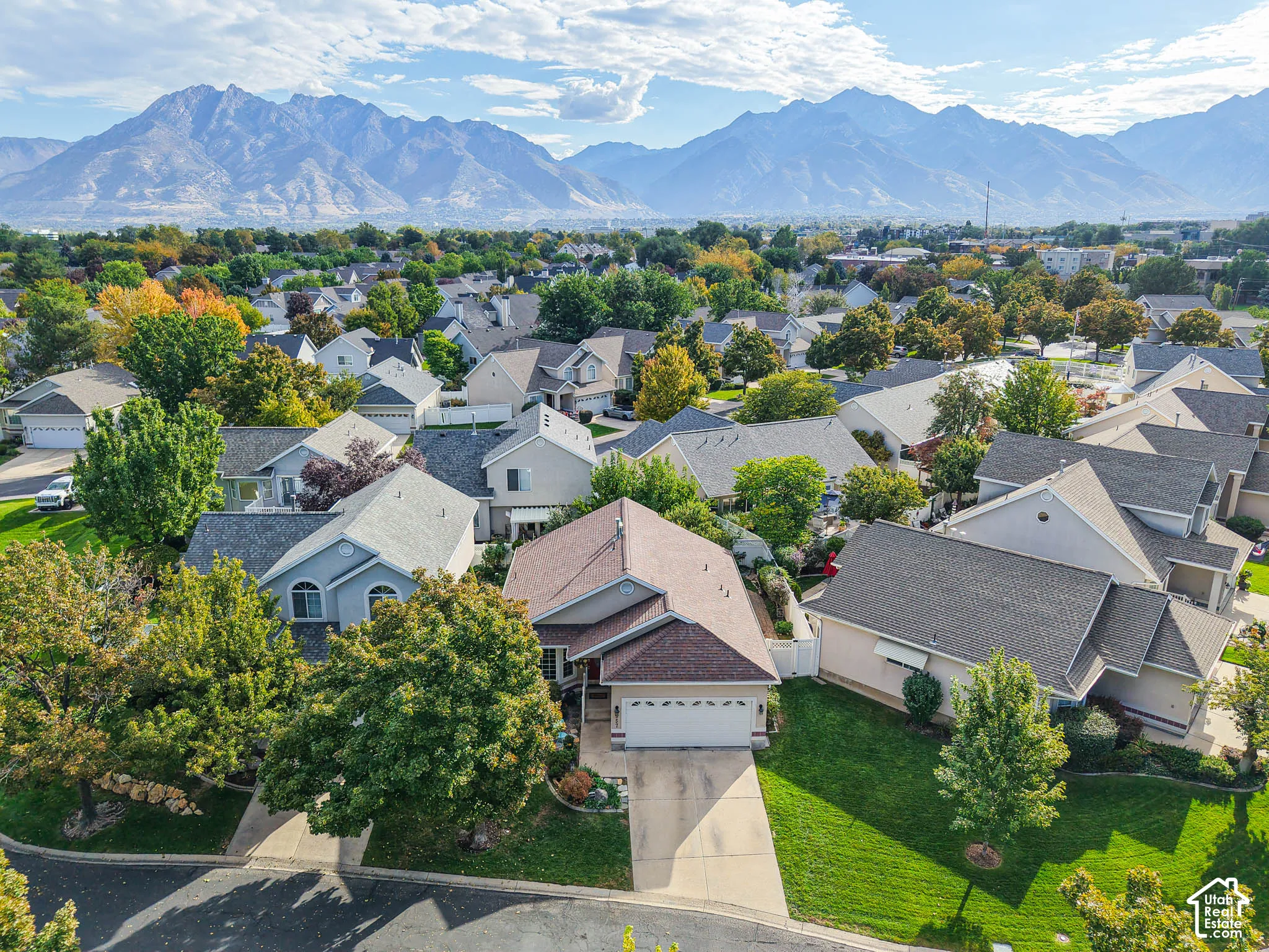 Residential neighborhood featuring detached homes with varied architectural styles, mature landscaping, and mountain scenery