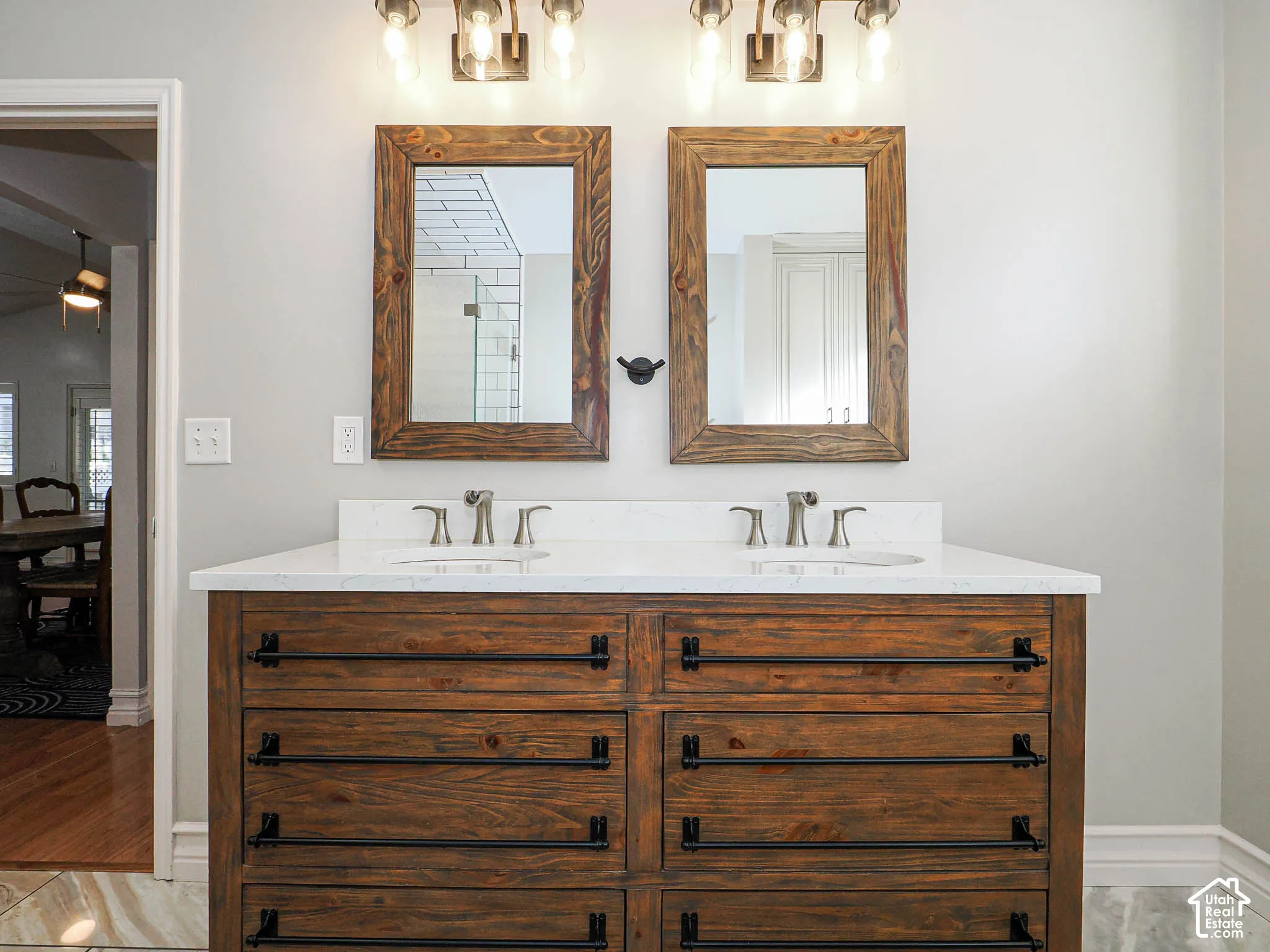 Dual wood-framed mirrors above a double vanity with stone countertop
