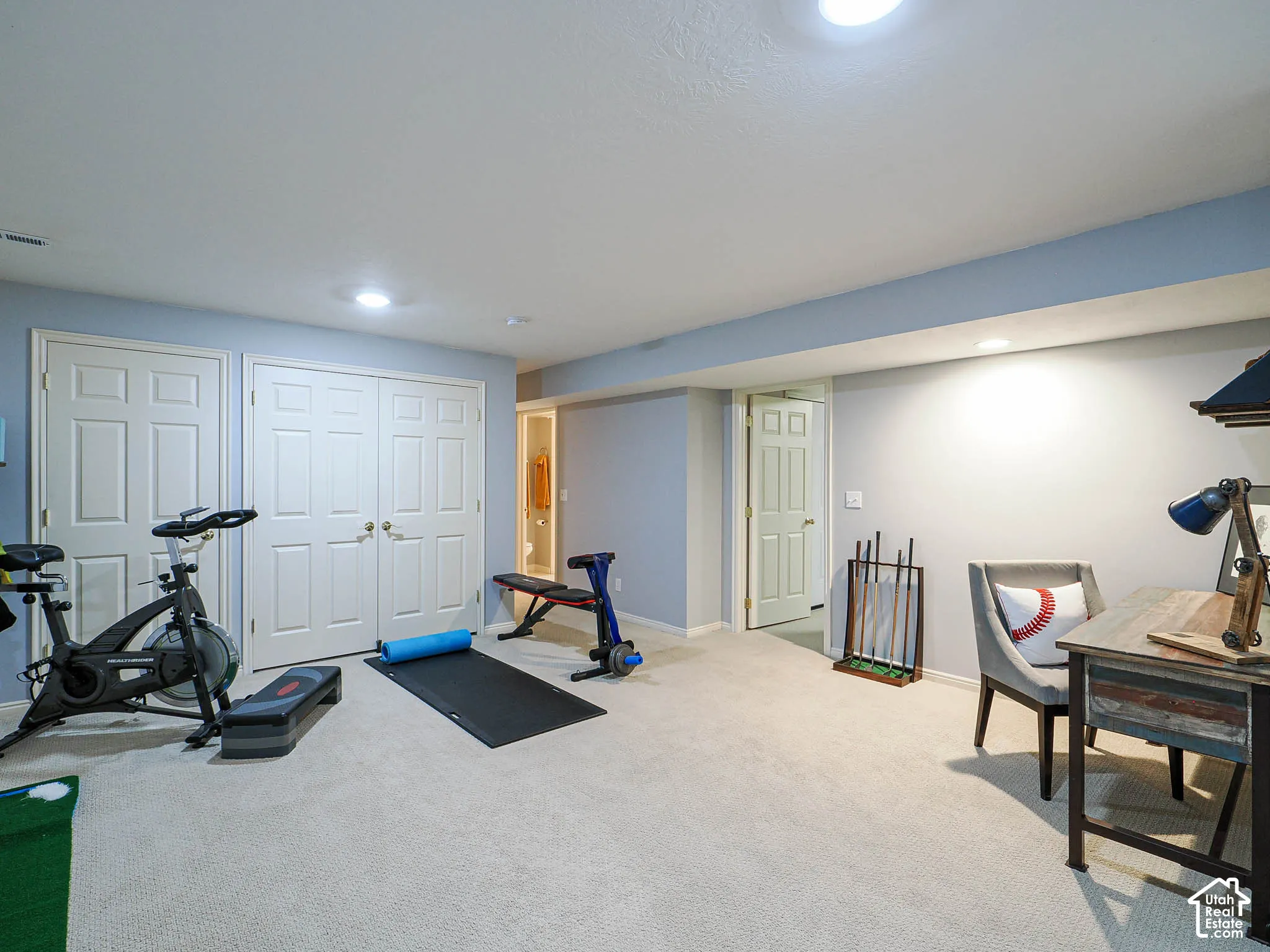Recessed lighting illuminates the carpeted flooring and light-toned walls