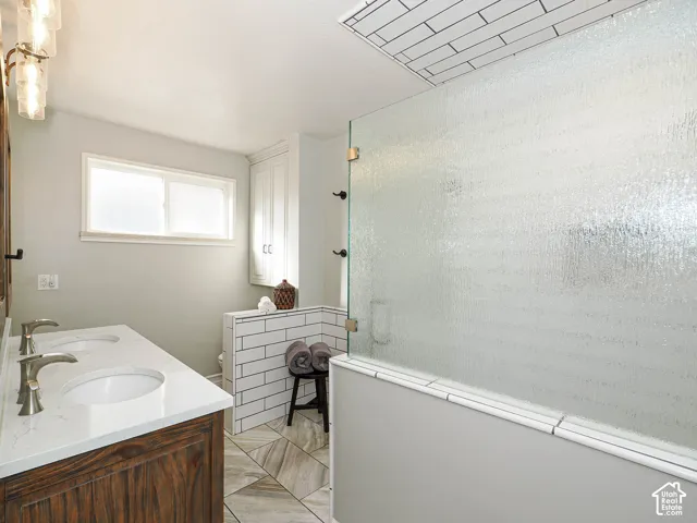 Dual vanity with undermount sinks, quartz countertop, wood-finish cabinetry, and brushed nickel fixtures